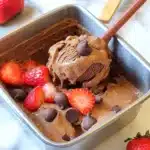 Chocolate strawberry nice cream with chocolate chips and sliced strawberries in a metal container