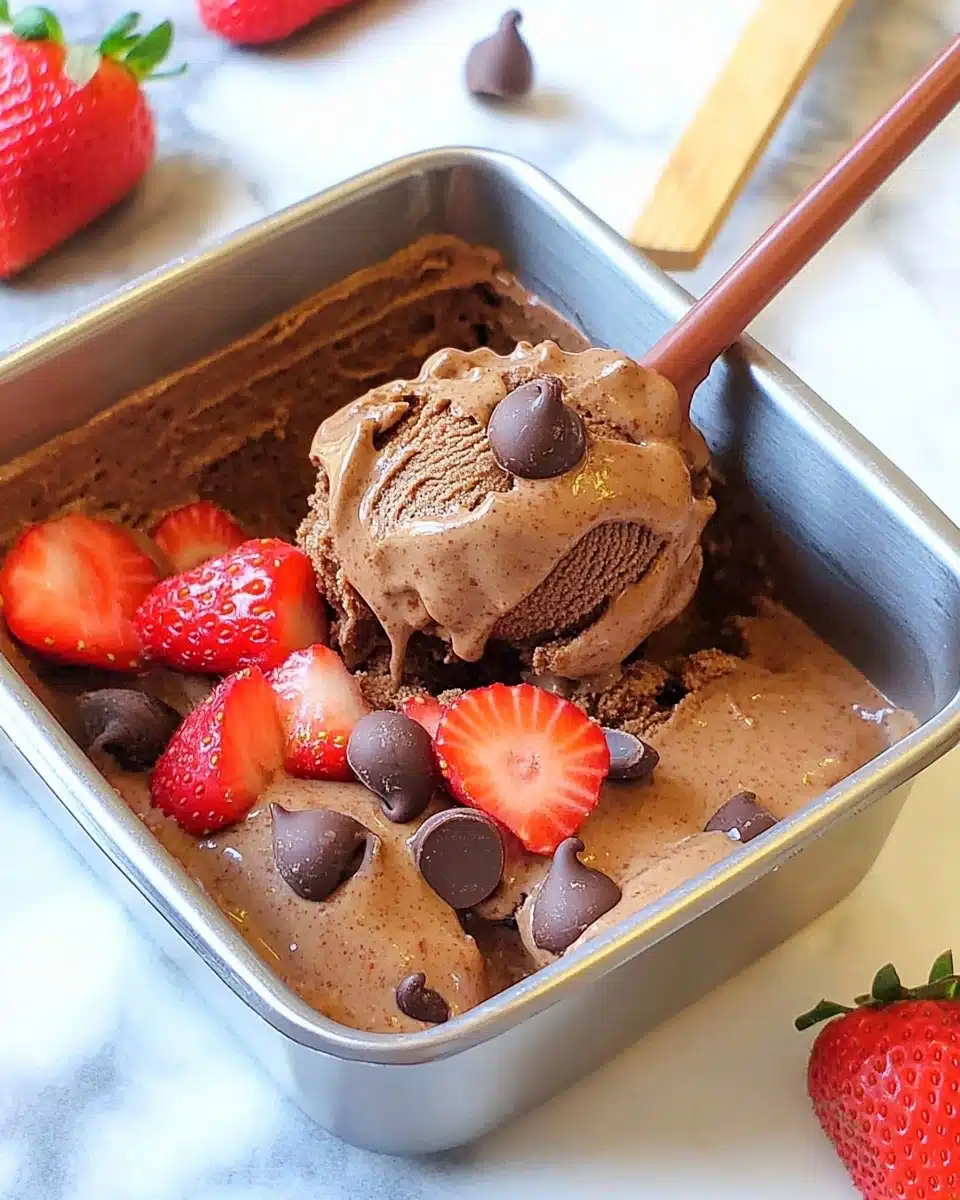 Chocolate strawberry nice cream with chocolate chips and sliced strawberries in a metal container
